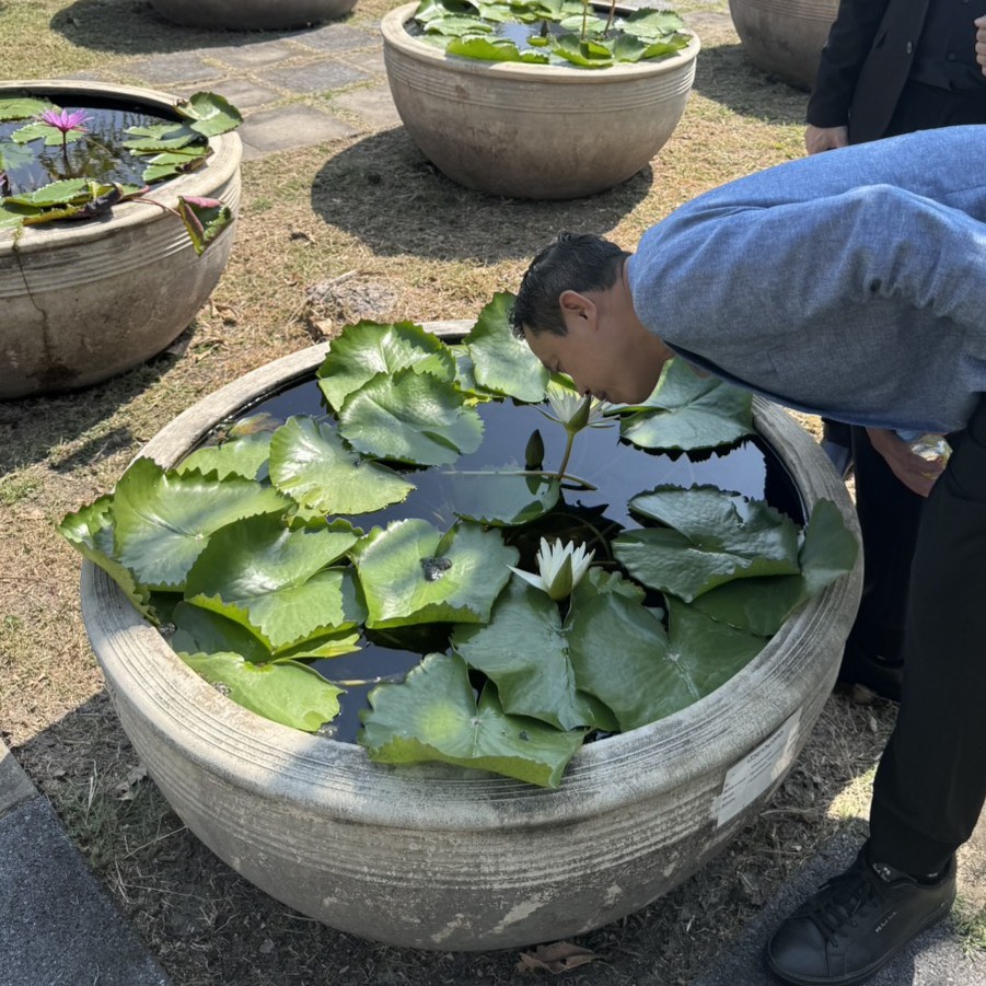 ดร.วรพล วังฆนานนท์ (ดร.เคี้ยง) ผู้ทรงคุณวุฒิด้านการแพทย์บูรณาการ ยืนในบริเวณพิพิธภัณฑ์บัว มทร.ธัญบุรี ในระหว่างการหารือแนวทางการวิจัยกลิ่นอโรม่าจากดอกบัว